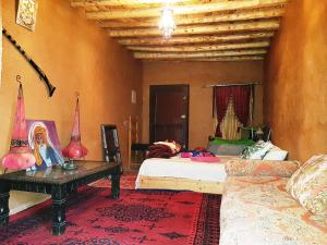 1 dormitorio con 2 camas, mesa y sofá en Tarmguist, en Aït Boukha