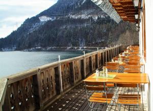 eine Reihe von Tischen und Stühlen auf einer Terrasse neben dem Wasser in der Unterkunft Hotel Karwendelblick in Urfeld