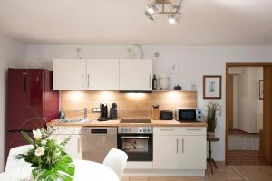 a kitchen with white cabinets and a sink and a table at Schnuckenstube Souterrain im Grünen in Schneverdingen