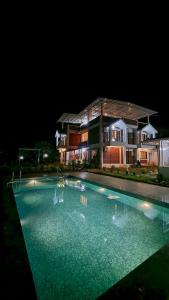 a large swimming pool in front of a house at night at Nisarg Forever Resort in Jāmb