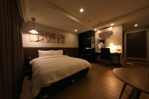 a bedroom with a bed and a desk and a chair at Kobos Hotel in Seoul