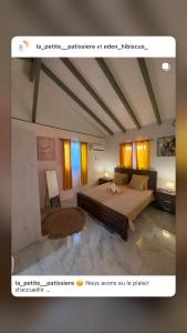 a bedroom with a large bed and yellow curtains at Eden hibiscus in Petit-Canal