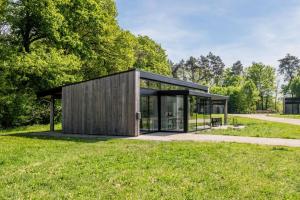 a small house with glass doors in a field at Landal Olde Kottink in Beuningen