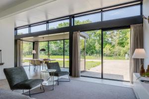 a living room with large windows and a table and chairs at Landal Olde Kottink in Beuningen