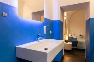 a bathroom with a white sink and a blue wall at La Dama del Castello in Bosa +44 photos