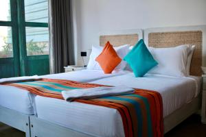 a bedroom with a large white bed with colorful pillows at Hotel Catamaran Bay by Ayur Ayur in Negombo +28 photos