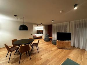 a living room with a table and a television at Ciasa Milandura NEW SUMMER 2025 in San Cassiano