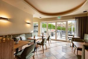 a restaurant with tables and chairs and a patio at Hotel Gänsleit in Söll