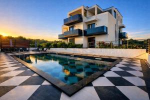 a villa with a swimming pool in front of a house at VILLA JANE INN in Rogoznica
