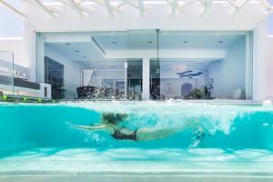a person swimming in the water in a swimming pool at Kivotos Mykonos - Preferred Hotels & Resorts in Ornos +25 photos