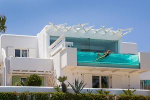 a man in a swimming pool on top of a house at Kivotos Mykonos - Preferred Hotels & Resorts in Ornos