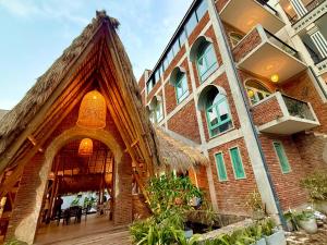 a large brick building with a thatch roof at Hotel Catamaran Bay by Ayur Ayur in Negombo