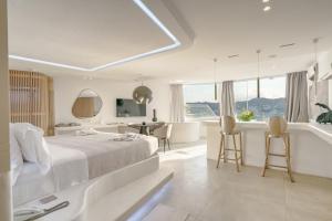 a white bedroom with a large bed and a bathtub at Kivotos Mykonos - Preferred Hotels & Resorts in Ornos