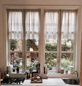 a kitchen window with white curtains and a sink at Viadelloca35 in Rome