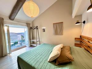 a bedroom with a green bed and a large window at La petite fontaine in Bédoin