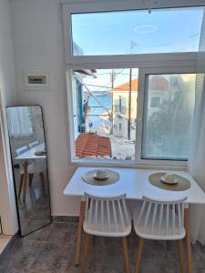 a white table and two chairs in front of a window at Perla in Pythagoreio