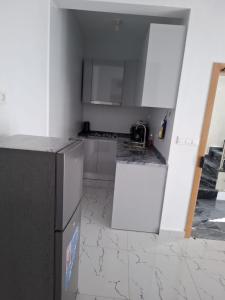 a kitchen with white cabinets and a black refrigerator at Chambre Double dans spacieux appartement in Tarrafal