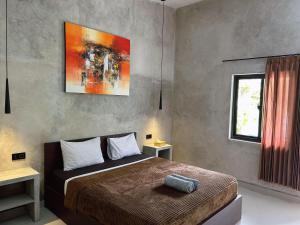 a bedroom with a bed and a painting on the wall at Sayang Bungalows in Kuta Lombok