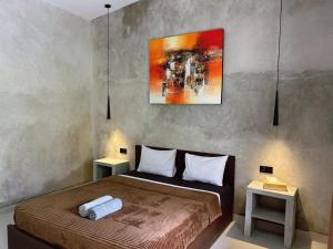 a bedroom with a bed with two tables and a painting at Sayang Bungalows in Kuta Lombok +49 photos