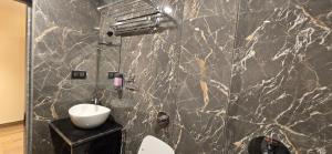 a bathroom with a marble wall with a sink and a toilet at Hotel Sunrise Muzaffarpur in Muzaffarpur