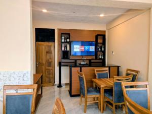 a dining room with a table and a television at Kiliscape Hotel Moshi in Uru
