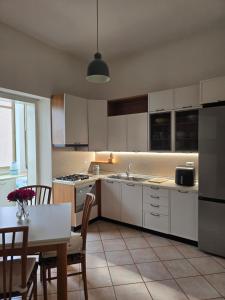 a kitchen with white cabinets and a table and a dining room at Alloggio turistico Dedicato in Gaeta