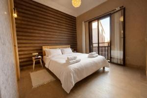 a bedroom with a large bed and a large window at Beach Mama Waky Marrakech Appartement Premium Piscine & Vue Atlas in Marrakesh