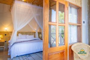 a bedroom with a bed and a glass door at Equator Lodge & Campsite in Kikorongo