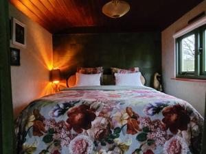 a bedroom with a bed with a floral bedspread at B&B 't Maartensdijkse Bos in Maartensdijk
