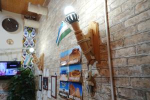 a street light on a brick wall with posters at Rasulboy Guest House in Khiva