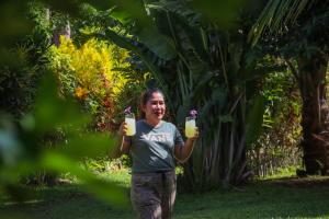 a man holding up two glasses of orange juice at Happy Coconut Camiguin in Mambajao