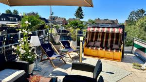 a patio with chairs and a table and an umbrella at Traveller Awards 2025-26 -- Nordeifel FW 75 m2 mit 50 m2 Terasse- Thermen-Badewelt, Phanasialand, Köln, Bonn, Eifelwanderung oder nur mal so zum entspannen in Euskirchen