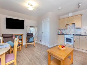 a living room with a kitchen and a table with a bowl of fruit at Harbour View in Cromarty