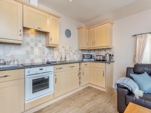 a kitchen with wooden cabinets and a couch at Harbour View in Cromarty