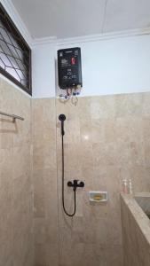a bathroom with a shower with a control board on the wall at Rumah Mewah Johar in Pontianak +43 photos