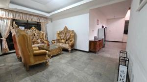 a living room with gold chairs and a table at Rumah Mewah Johar in Pontianak