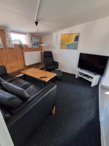 a living room with a couch and a table and a tv at Strandens Apartment in Ishøj