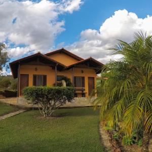 a yellow house with a palm tree in front of it at Pousada Alem das Formas in Carrancas