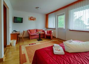 a bedroom with a red bed and a living room at Hotel Seeschlösschen in Groß Köris