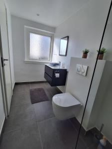 a bathroom with a toilet and a sink and a window at Strandens Apartment in Ishøj +5 photos