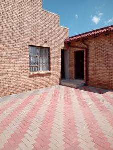 a brick building with a window and a brick driveway at Nkotsha The Palace in Diepkloof