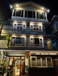a man standing in front of the village bakery at night at Hotel white lion-Near Bhajra Taxi Stand in Gangtok