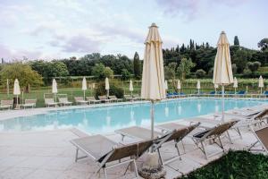 a swimming pool with lounge chairs and umbrellas at Agriturismo Le Caldane in Colà di Lazise