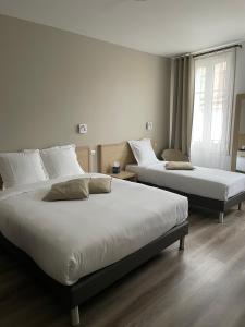 a bedroom with two beds and a window at Hôtel Du Commerce in Fécamp