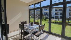 a glass table and chairs on a balcony with windows at 7 Topanga in Uvongo Beach
