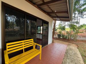 a yellow bench sitting on the porch of a house at Honey Zen Zone in Ko Mak