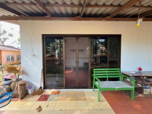 a green bench sitting on the front porch of a house at Honey Zen Zone in Ko Mak