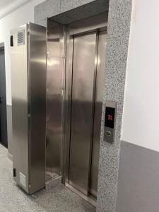 a metal elevator in a building with a clock on it at Confort Suite in Alba Iulia