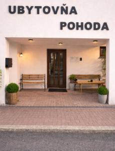 a building with two benches in front of a door at Pohoda Stay in Revúca