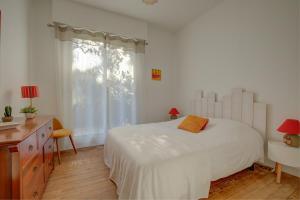 a bedroom with a white bed and a desk and a window at Maison des Abatilles- Bassin Arcachon in Arcachon